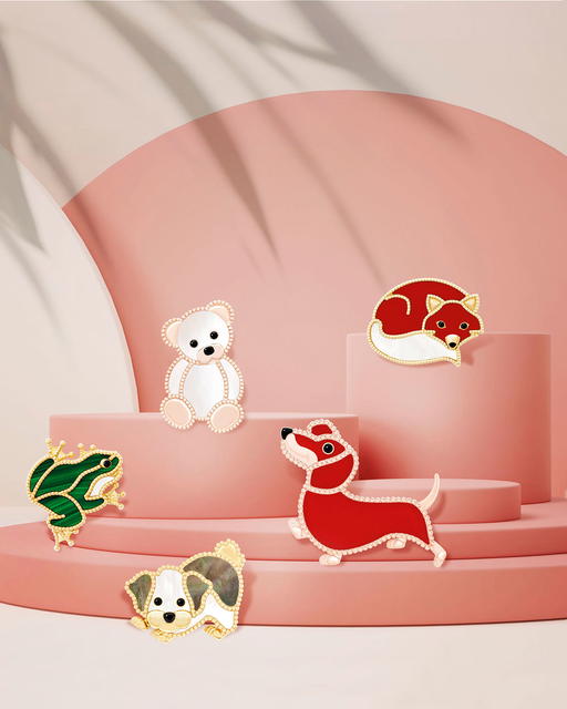 (clockwise from top left) Teddy bear clip (rose gold with mother-of-pearl, and onyx), Fox (yellow gold with carnelian, mother-of-pearl, and onyx), Dachshund (rose gold with carnelian and onyx), Bichon Frisé (yellow gold with grey and white mother-of-pearl, and onyx), and Frog (yellow gold with malachite, mother-of-pearl, and onyx) (Credit: Van Cleef & Arpels)