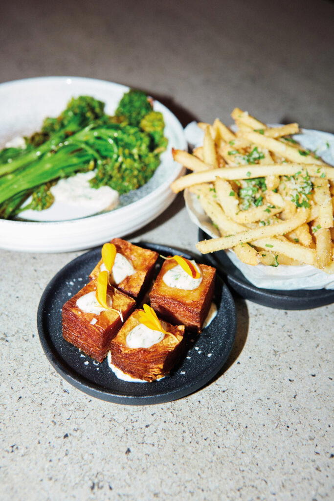Sides of truffle parm fries, charred broccolini, and crispy potato pavé