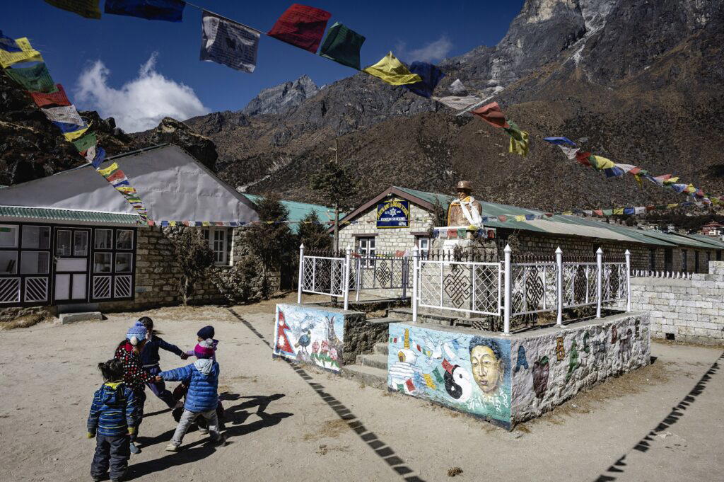 Some children play in front of Edmund Hillary’s statue at Khumjung School. Hillary worked closely with the local Sherpa community and founded schools, hospitals and health clinics across the region (Credit: Rolex/ Franck Gazzola)