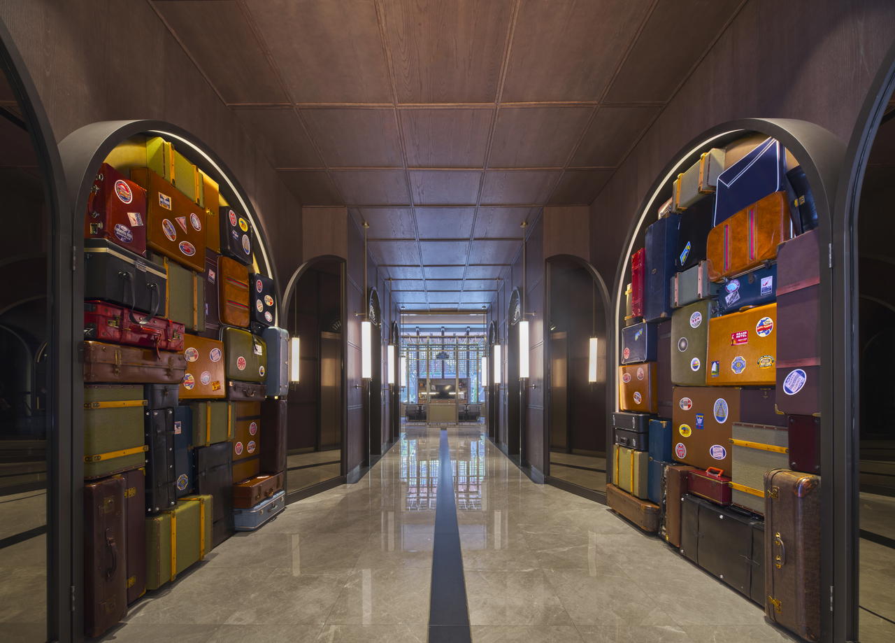 A floor-to-ceiling installation of vintage carriers flanks the marble- and wood-clad walkway