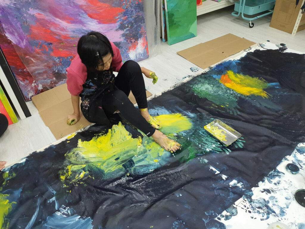 Genine paints with her hands and legs