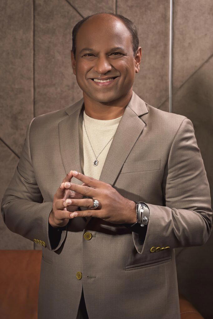 Ismail wears the Old World Charm Signature necklace in white gold with diamonds, the Deco Centennial Skylight Cigar band in white gold with diamonds, and the Azimuth Land Cruiser timepiece (Credit: UltraLuxe)