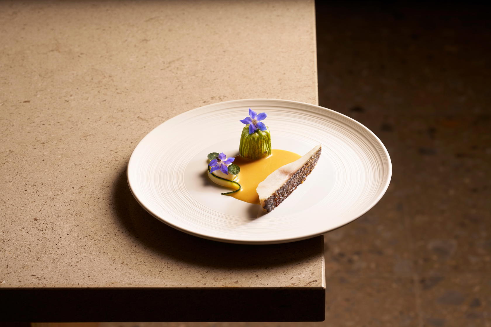 In Isaki, sustainable Japanese grunt is pan seared and served with a zucchini flower stuffed with scallop mousse, pickled zucchini, and Nyonya beurre blanc (Credit: Loca Niru)