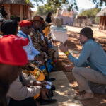 Boyes in a discussion with Angolan kings and chiefs from the banks of the Zambezi River. The kings were joined by dignitaries and global leaders at the 2025 Ramsar Convention, where he presented pioneering research showing the overlooked role of the Angolan Highlands in the Zambezi’s flow (Credit: Rolex/Aurélie Marrier d’Unienville)