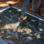 Boyes pointing to a river section on a map of Central Africa while at Victoria Falls. “Up in the Angolan Highlands we’re working alongside traditional leaders to better protect a landscape larger than England,” he says (Credit: Rolex/Aurélie Marrier d’Unienville)